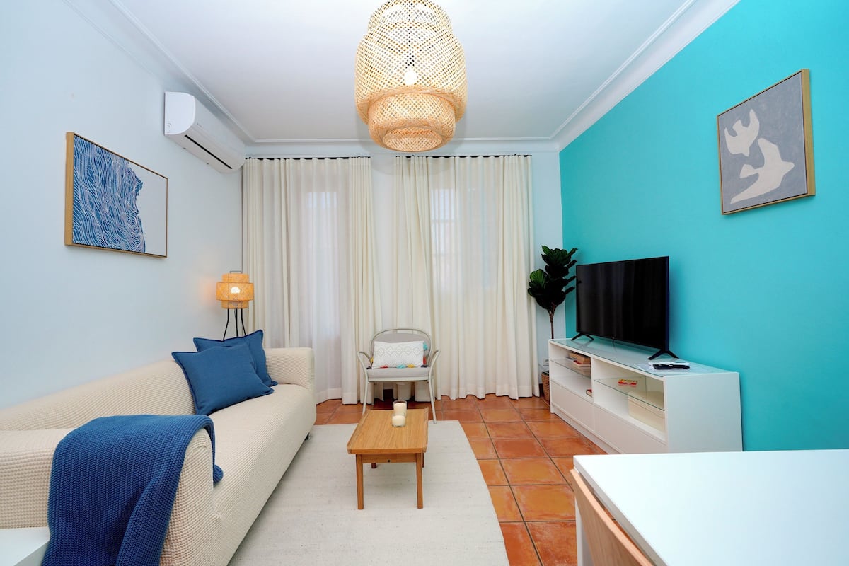 A living room with a sofa, a coffee table, a TV stand, and a chair.