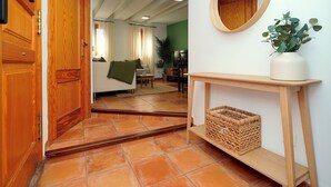 Una puerta de madera, un espejo, una planta y una cesta de mimbre.