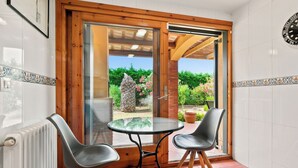 Ein Zimmer mit Glastür und Zugang zu einer Terrasse, auf der ein Tisch und zwei Stühle stehen.