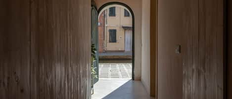 A hallway with wooden walls, a tiled floor, and an arched doorway leading to an outdoor area.