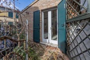 Une maison en briques avec un patio carrelé, une porte-fenêtre coulissante et un portail en métal.