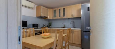 A modern kitchen with wooden cabinets, a stainless steel refrigerator, and a dining table with chairs.