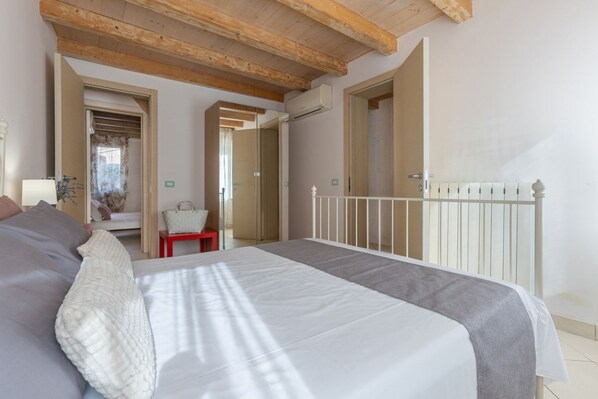 Une chambre à coucher avec un lit, une petite table et une chaise. Le plafond est en bois et il y a un radiateur blanc.