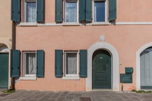 Un bâtiment avec une porte verte, de nombreuses fenêtres dotées de volets verts et une boîte aux lettres.