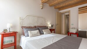 A bedroom with a bed, two bedside tables, a nightstand, a lamp, a clock, and a door.