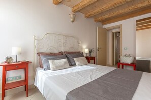 A bedroom with a bed, two bedside tables, a nightstand, a lamp, a clock, and a door. - GuestHost - A comfortable and welcoming 75 square meters apartment with a large courtyard and private entrance, perfect for six people, located on the ground floor of a renovated historic building facing the canal (NOT accessible by car).The property enj (Comacchio)