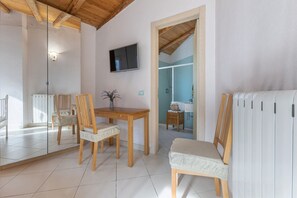 Una habitación con techo de madera, una mesa de comedor con sillas, un televisor y una pared espejada.