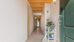 Un pasillo con techo de madera, una puerta verde y una planta en un estante.