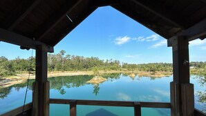 A wooden structure with a view of a calm lake and surrounding forest. - Cozy, Piney Woods Barndo Studio in Silsbee--4 minutes from town. (Silsbee)