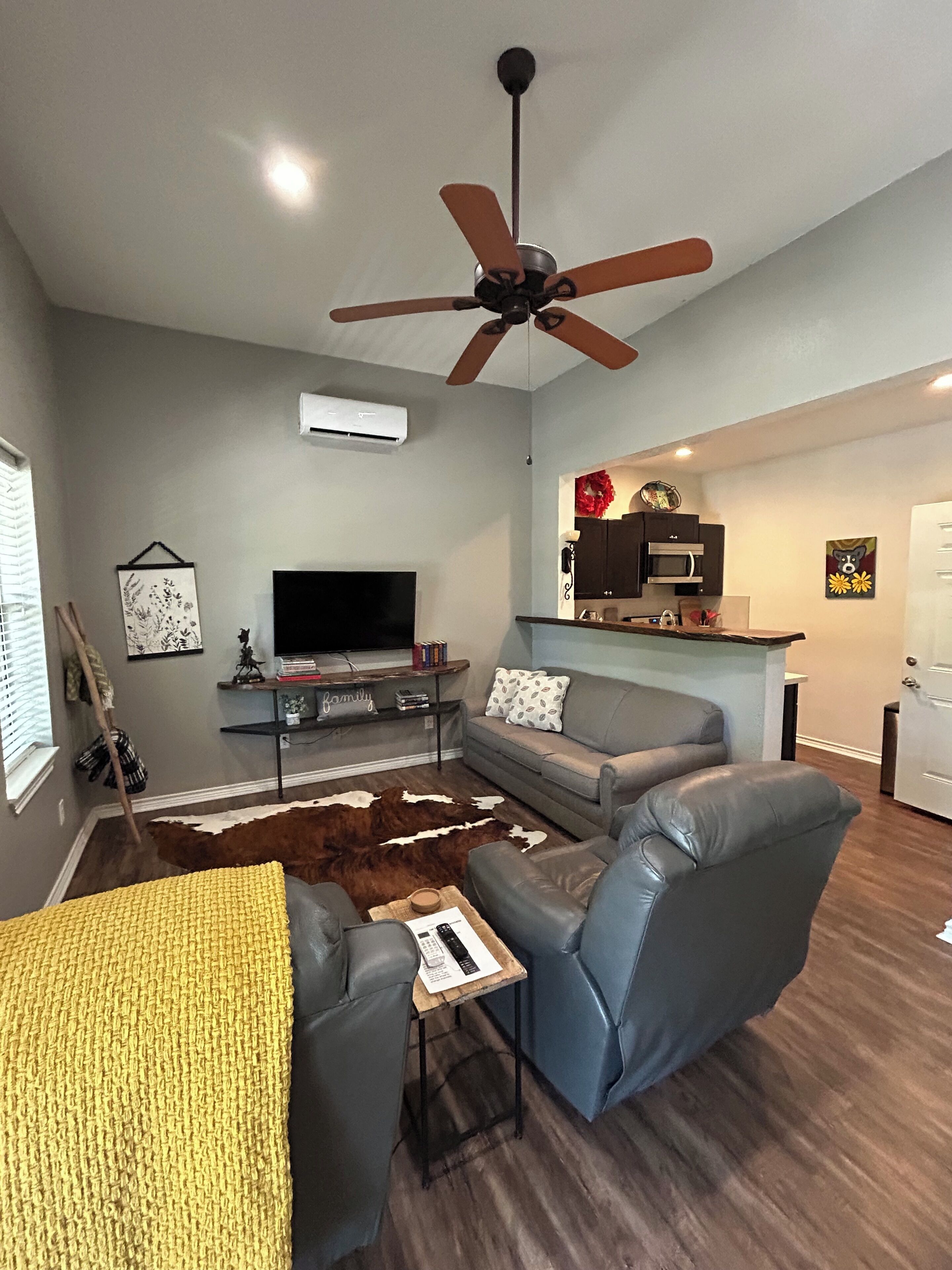 A living room with a ceiling fan, a flat-screen TV, a sofa, a coffee table, and a fireplace.