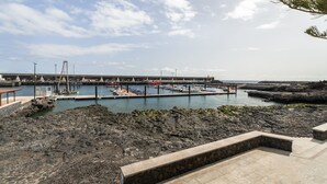 Una marina con barcos amarrados, una costa rocosa y un muelle que se adentra en el agua.