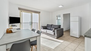Un apartamento moderno con comedor, sofá, televisor y refrigerador.