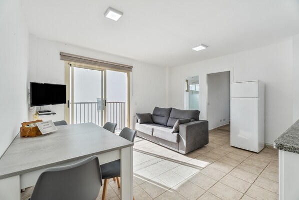 Un appartement moderne comprenant un coin repas, un canapé, une télévision et un réfrigérateur.