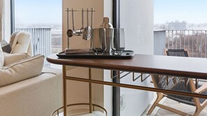 Ein modernes Zimmer mit einem Holztisch, einer Metallstange und Blick auf die Stadt durch große Fenster.
