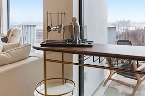 A modern room with a wooden table, a metal bar, and a view of the city through large windows. - Penthouse River View Condo with Patio + Parking, Downtown (Nashville)