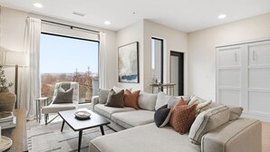 Ein modernes Wohnzimmer mit großem Fenster, einer Sofagarnitur, einem Couchtisch und Blick auf eine Brücke.