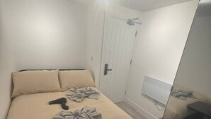 Een slaapkamer met een bed, nachtkastje, spiegel en radiator.