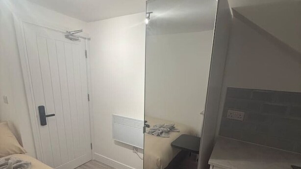 Een slaapkamer met een bed, nachtkastje en een spiegel.