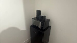 A compact kitchenette with a black refrigerator, microwave, and coffee maker.
