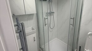 A modern bathroom with a glass-enclosed shower, a toilet, and a sink.