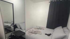 Ein modernes Hotelzimmer mit einem großen Bett, einem Nachttisch, einem Sessel, einem Spiegel und einer Deckenleuchte.