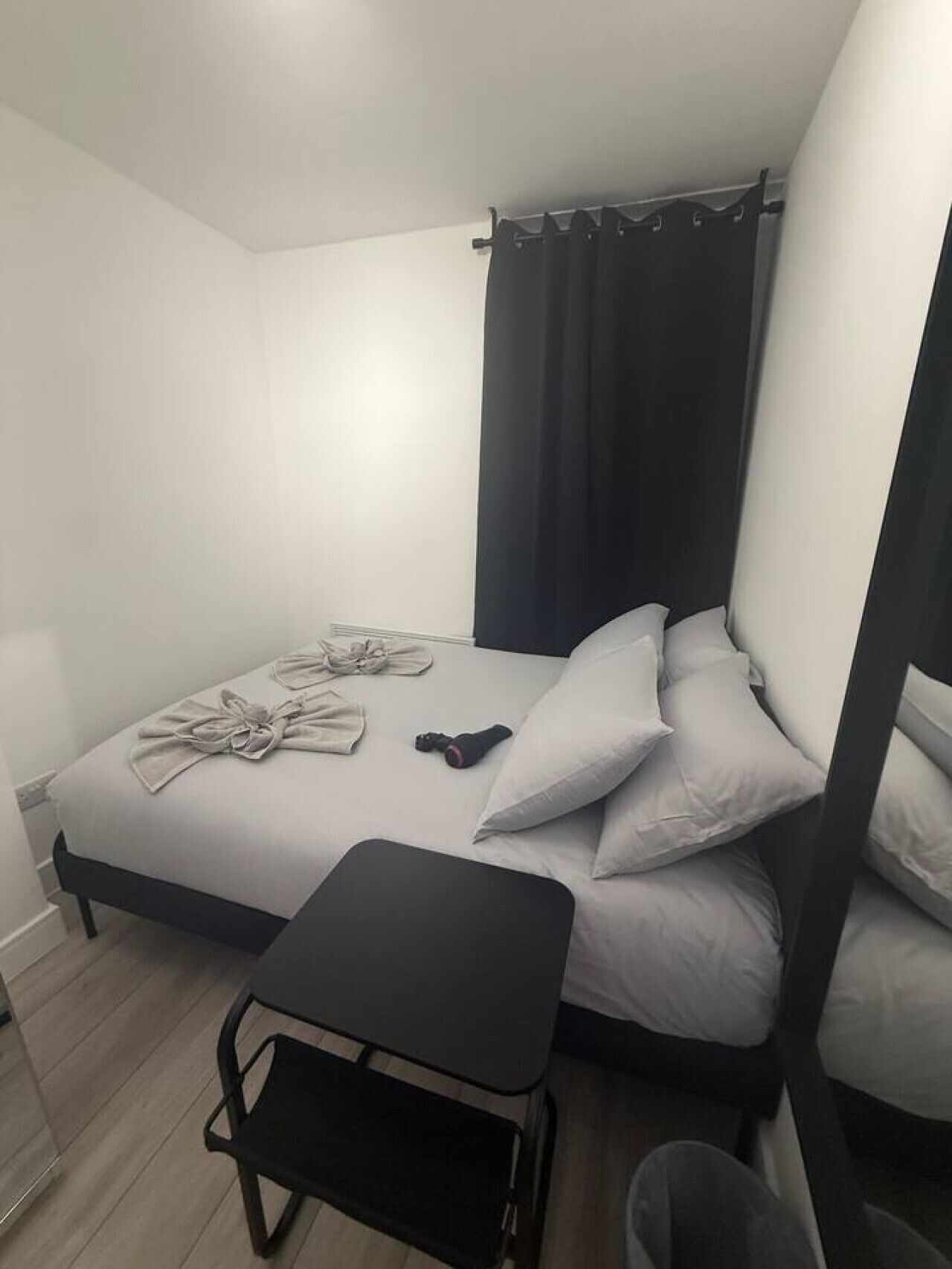 Une petite chambre à coucher, bien rangée, avec un lit, des oreillers, une petite table et une chaise.