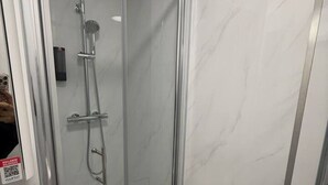 Eine Duschkabine mit Glaswänden und einer Handbrause.