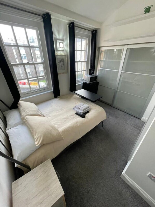 A bedroom with a bed, a desk, a chair, a wardrobe, and a window. - London Bridge Shard En-Suite (Greater London)