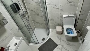 A bathroom with a glass-enclosed shower, a toilet, and a sink. - Central London room w kitchen (Greater London)