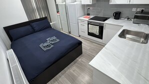 A compact hotel room with a bed, kitchenette, and a small bathroom. - Central London room w kitchen (Greater London)