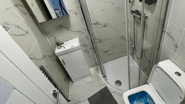 A modern bathroom with a glass-enclosed shower, a toilet, a sink, and a mirror. - Central London room w kitchen (Greater London)