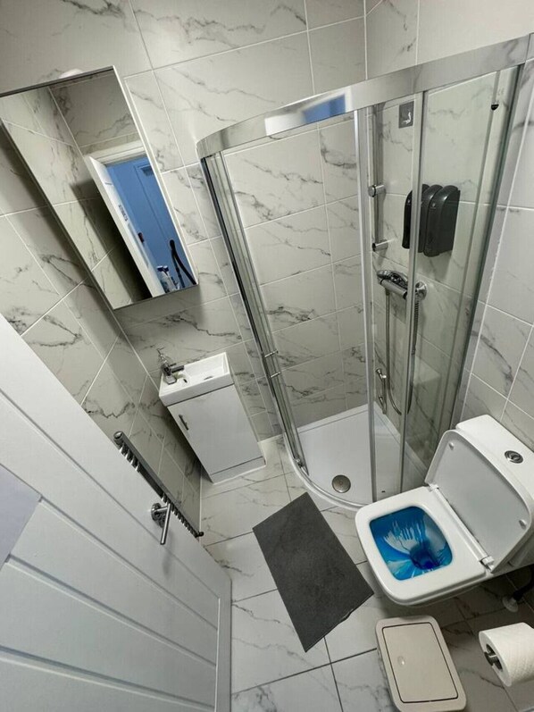 Ein modernes Badezimmer mit einer Duschkabine, einer Toilette, einem Waschbecken und einem Spiegel.