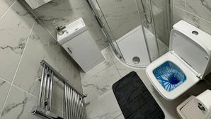 A modern bathroom with a glass-enclosed shower, a toilet with a blue seat, and a sink with a soap dispenser. - Central London room w kitchen (Greater London)