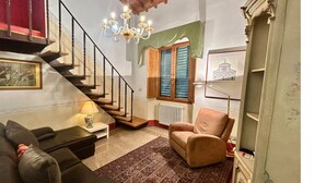 Un escalier menant à un deuxième étage, un canapé, une chaise, une lampe et un radiateur.