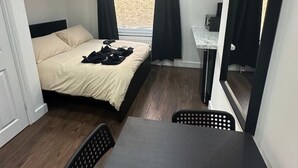 A compact bedroom with a single bed, a small desk, a chair, and a large mirror. - Battersea Park London room (Greater London)