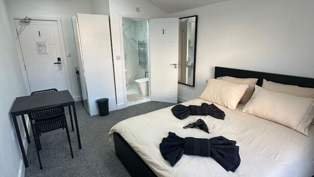 Ein modernes Hotelzimmer mit einem großen Bett, einem kleinen Schreibtisch und einem separaten Badezimmer.