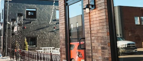 A building with large windows, a brick facade, and a metal fence.