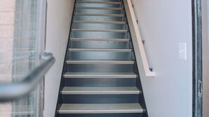 A staircase leading to an upper floor, with a handrail on the right and a glass door on the left.