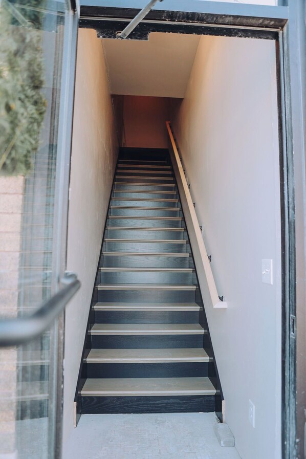 A staircase leading to an upper floor, with a handrail on the right and a glass door on the left. - Holland Loft #1 (Williamstown)