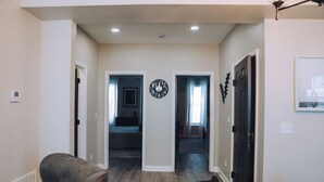 A hallway with a clock, a door, and a chair.