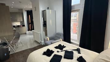 A hotel room with a large bed, a desk, and a view of the city.