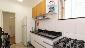 Eine Küche mit weißen Schränken, einer schwarzen Arbeitsplatte, einem Herd und einem Kühlschrank.