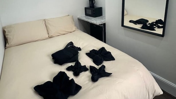 A hotel room with a bed, a nightstand, a mirror, and a small table with a coffee maker. - London zone 2 Private room (Greater London)