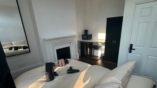 Ein Schlafzimmer mit einem großen Bett, einem Kamin, einem Schreibtisch und einer Tür.