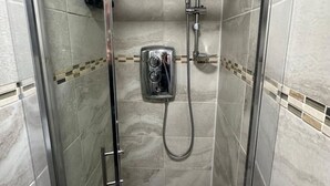 Eine begehbare Duschkabine mit Handbrause und einer fest installierten Bedienkonsole.