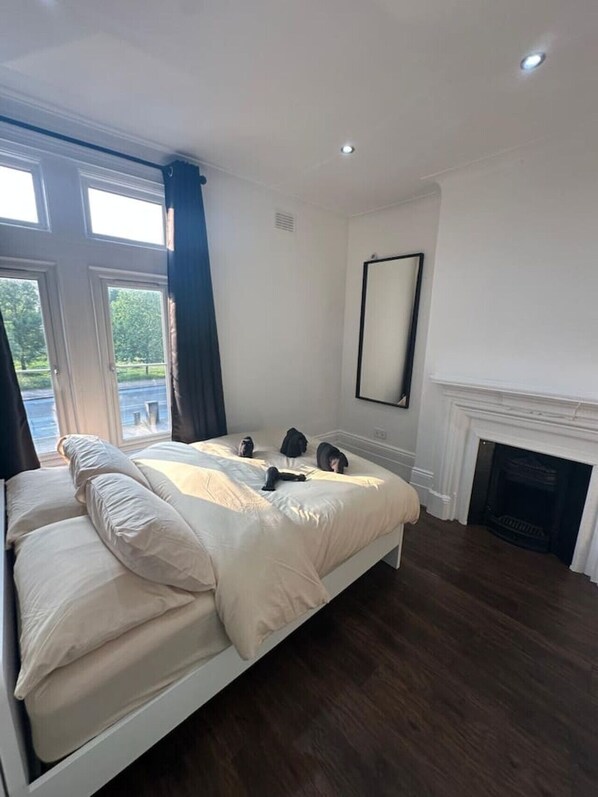 A bedroom with a large bed, a fireplace, and a view through the window.
