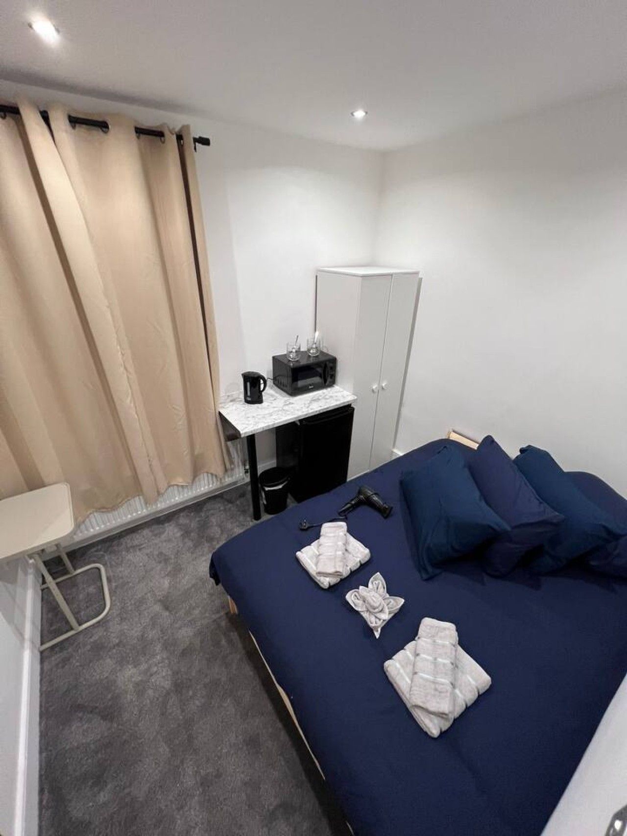 Une chambre d’hôtel équipée d’un lit, d’un bureau, d’une armoire et d’une machine à café.