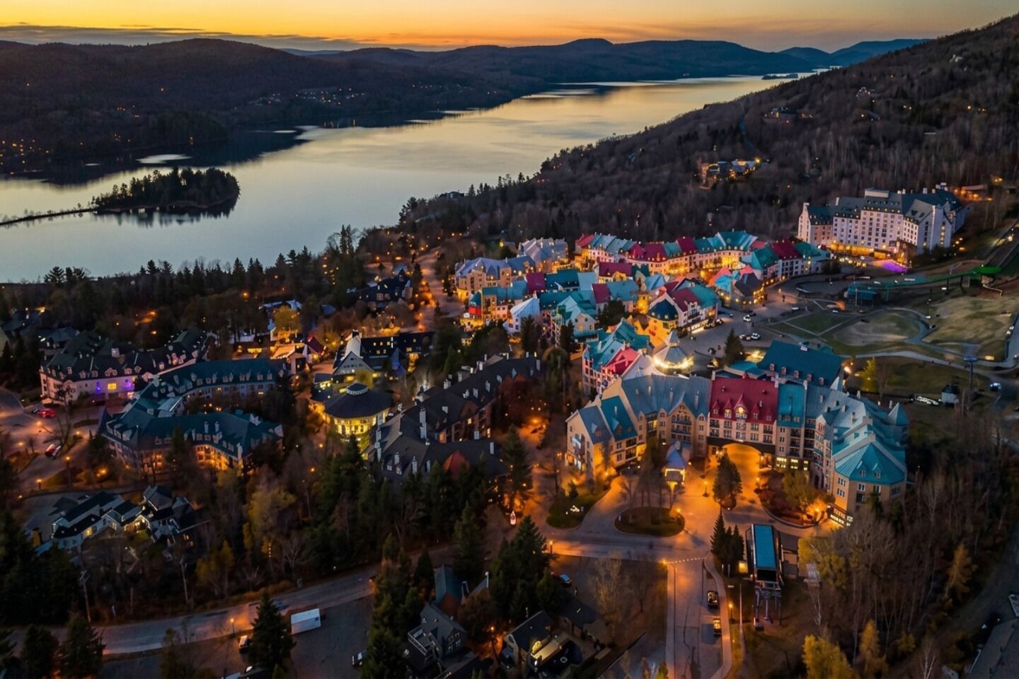 Et resort med flere bygninger, en sø og et bjergrigt baggrundslandskab.