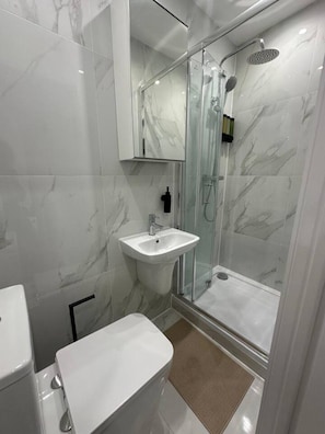 A modern bathroom with a glass-enclosed shower, a white sink, and a toilet.