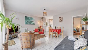 Una sala de estar moderna con un sofá, sillas, una mesa de comedor y una cocina al fondo.